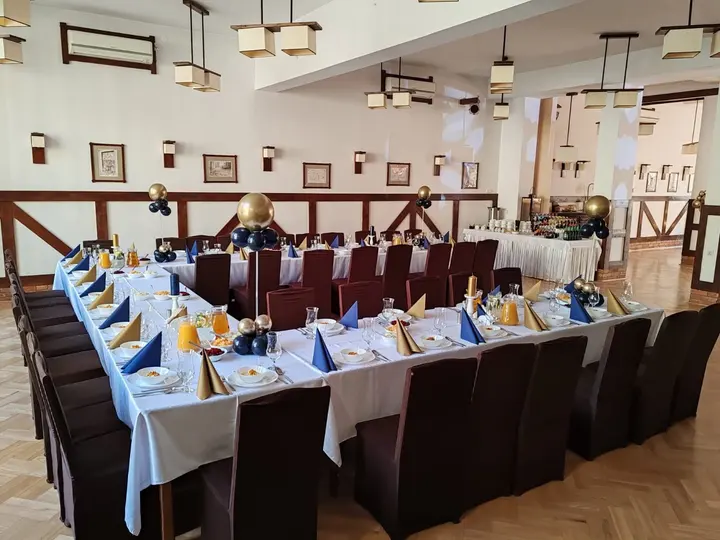 Sala bankietowa z białymi obrusami, przygotowana na przyjęcie